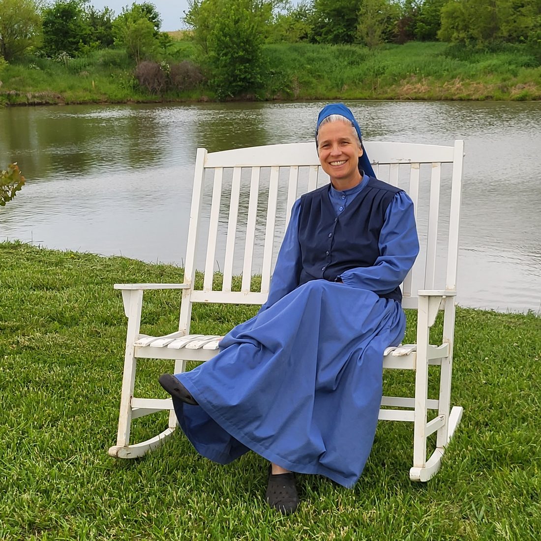 Heather seated on a bench beside a pond