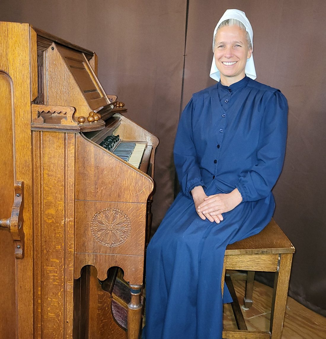 Heather seated beside a pump organ